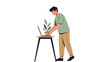 © Niken - Man placing plant pot on a table next to a laptop computer, vector illustration, white background