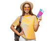 © Damir Khabirov - Happy young woman in sunglasses and summer clothes wearing backpack and holding airplane tickets, ready for travel