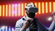 © DC Studio - Artsy young guy immersed in virtual reality under neon lights and cyberpunk glow, blending street style with modern fashion and technology in a cool setting full of aesthetic visuals. Camera A.