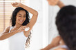 © Prostock-studio - A woman is happily applying deodorant while standing in front of a mirror. The sunlight streams through the window, enhancing the serene atmosphere of her bathroom routine.