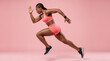 © Przemek - Dynamic African American Woman Running in Activewear Against Pink Background