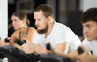 © JackF - Bearded man hardly perform exercise on stationary bicycle, pedaling and exercising in fitness class. Fitness equipment, visitors engaged in physical task during training