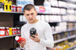 © JackF - Focused young guy choosing a bottle of vitamin supplements in large sports nutrition store