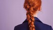 © hen - A person with red hair styled in a long braid wears a blue shirt, standing against a neutral background.