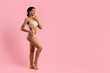 © Anastasiya - Smiling young black woman posing in beige underwear on pink studio background. Fit body, soft lighting and confident expression suitable for beauty, wellness and lifestyle projects