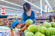 © unai - Mother and son choosing watermelon in supermarket
