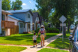 © unai - Mother and son walking on sidewalk in residential neighborhood