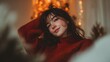 © Sobah - Young woman with dark hair wearing a warm sweater smiles softly against a backdrop of gentle festive lights