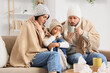 © Pixel-Shot - Sick family with warm plaid sitting on sofa at home