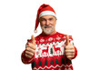 © opolja - Merry satisfied smiling mature man wear knitted christmas sweater Santa hat posing showing thumb up like gesture wink isolated on transparent background Happy New Year 2026 celebration holiday concept