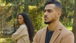 © Yuliia - Frustrated Hispanic man offended angry separating from upset Arabian woman couple conflict in autumn park date sad boyfriend husband with girlfriend wife outdoors family quarrel ignoring each other