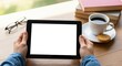 © MAHFUJ - Person holding digital tablet at cozy workspace with coffee and books
