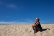 © PeeJee - Frau sitzt auf Sanddüne