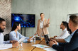 © Prostock-studio - Colleagues from different backgrounds gather in a modern boardroom to brainstorm and develop strategies. One speaker presents data on a screen, engaging others in meaningful discussions.