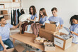 © Prostock-studio - Five volunteers are actively sorting through donations in a community room. They are organizing clothes, blankets, and food items into various boxes. Smiles and teamwork create a positive atmosphere.