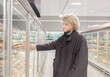© lado2016 - Man choosing frozen food from a supermarket freezer., reading product information