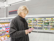 © lado2016 - Man choosing frozen food from a supermarket freezer., reading product information