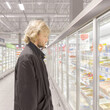 © lado2016 - Man choosing frozen food from a supermarket freezer., reading product information
