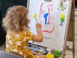 © Pavel Losevsky - Little girl is painting a picture. She is wearing a yellow dress. The picture is on a white board