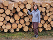 © Pavel Losevsky - Woman stands in front of a pile of logs. She is wearing a gray jacket and brown pants