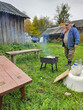 © Pavel Losevsky - Man is standing in front of a grill. The grill is on a table. The man is smoking