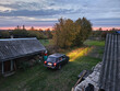 © Pavel Losevsky - Black car is parked in a grassy area. The car is in front of a house with a roof on sunset dusk