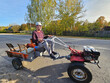© Pavel Losevsky - Man is riding a tractor on the road. The tractor has a red engine and is pulling a trailer in village