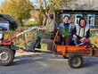 © Pavel Losevsky - Man and two women are riding in a truck. The gasoline bike truck is orange and has a trailer attached to it