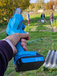 © Pavel Losevsky - Person is holding a blue tool electric saw with the number 21 on it. There are other people in the background