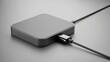© Tanakorn - Sleek minimalist grey electronic device connects to a black USB cable on a clean studio surface, embodying modern technology design elegance and efficiency