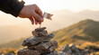 © Dmytriy - Metaphor of conquering the peak. A human hand marks the reached height with a small flag on balancing stones