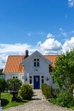 Traditional White Wooden House with Blue Door and Cobblestone Path in Son Norway