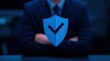 © oksa_studio - Blue security shield with check mark in front of business man in suit for protection and verification concepts cybersecurity and data privacy