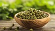 © Nany - A wooden bowl filled with green peas on a rustic wooden table with a blurred green leafy background.