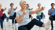 © SYATRI RAWU - Active senior citizens engaged in a chair exercise class, promoting health and vitality through synchronized movements for a vibrant lifestyle