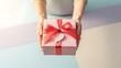 © ZiletterId - Hands present a pink gift box tied with a red ribbon and heart tag