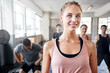 © peopleimages.com - Fitness, happy and portrait of woman in gym with personal trainer for workout, wellness or training. Confident, smile and female person with group for pride with exercise or health in sports center.