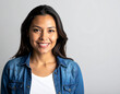 © BNMK0819 - Smiling young woman with dark hair wearing a denim shirt and white t-shirt against a plain background