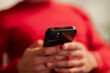 © Studio Marmellata - A person in a red shirt holds a black smartphone, focusing on the device's camera lens.
