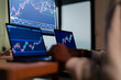 © Studio Marmellata - A person's hands are visible as they work on multiple computer screens displaying financial charts and data, suggesting analysis or trading.