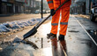 © justsann - Worker in orange uniform shoveling snow from a wet street.