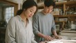 © CYBERPINK - Young man and a young woman working together in a workshop. they are standing in front of a table with various tools and materials scattered across it.
