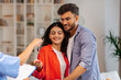 © Home-stock - Real estate agent giving keys to young indian buyers, happy woman taking key of future new apartment, spouses buying new house