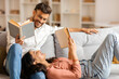 © Home-stock - Indian man and woman reading books while resting on comfy sofa, spouses enjoying leisure time at home on weekend