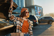 © SHOTPRIME STUDIO - Woman by car trunk with shopping bags at sunset in urban parking, beanie and sunglasses, candid lifestyle portrait with authenticity, golden hour glow and mindful living vibe.