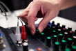 © Евгений Вершинин - Closeup of hands adjusting mixer with glowing LED indicators and cables, Detailed image of operator controlling mixer dials and monitoring sound through sensors and LEDs