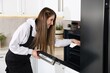 © New Africa - Woman wiping oven with paper towel in kitchen