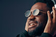 © SHOTPRIME STUDIO - Happy young man enjoying music with headphones, wearing stylish sunglasses against a dark background, vibrant emotions, modern style and contemporary concept