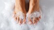 © Deliciafyneen - Bare feet submerged in a frothy, white, bubbling soapy bath or foot soak