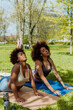 © Drobot Dean - Two female friends stretching their backs while lying and resting their hands on mats with eyes closed